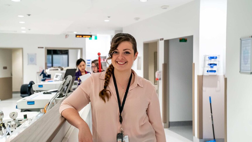 Rachel Middleton stands in the corridor in the Gorman unit at St Vincent's Hospital, she is wearing a pink blouse and smiling.
