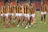 A group of AFL players walk off looking glum after losing a match.