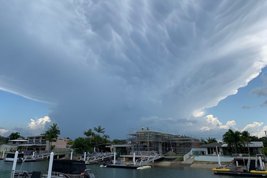 Storm clouds over Maroochy Waters with large clouds dwarfing a house under construction