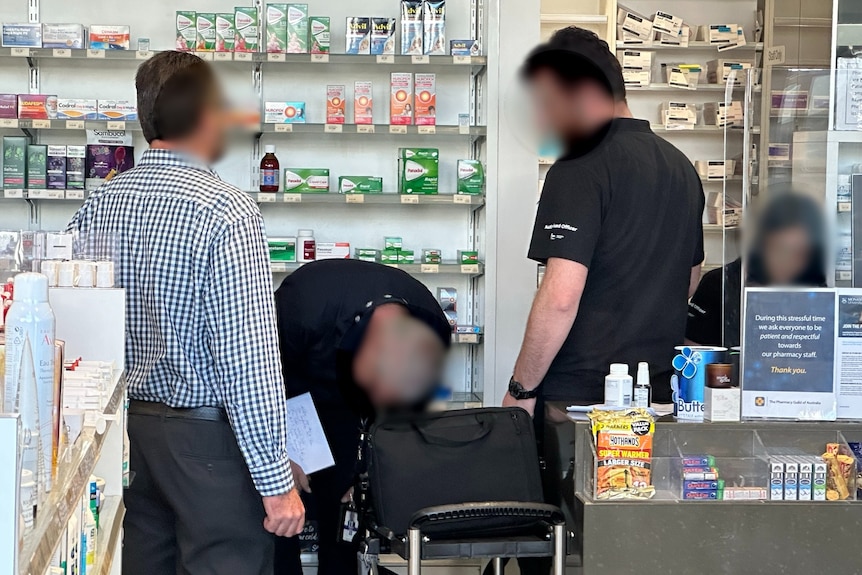 Four people are seen inside a pharmacy during a raid
