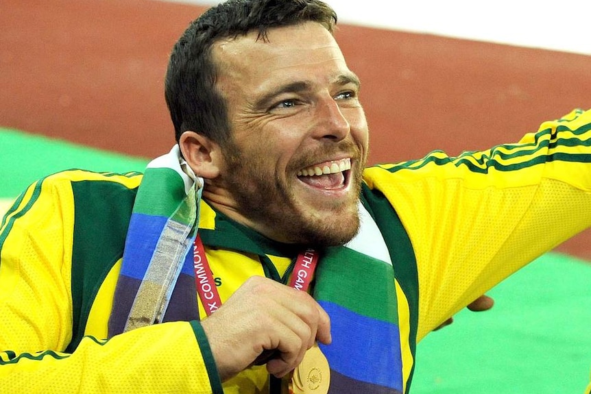 Paralympian Kurt Fearnley holds a gold medal.