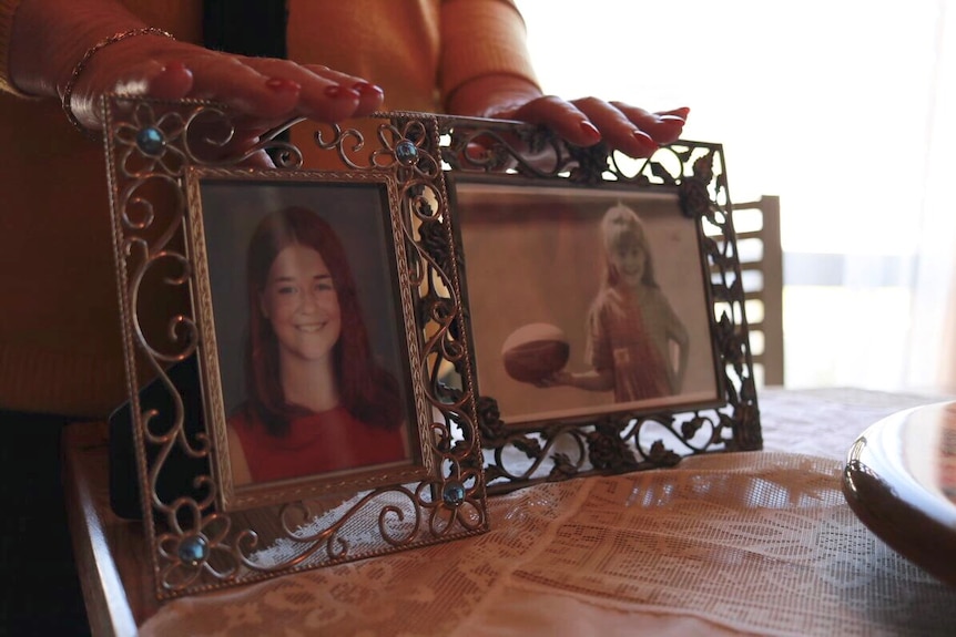 Sylvia's hands touching photos of her daughter Clare, before she died.