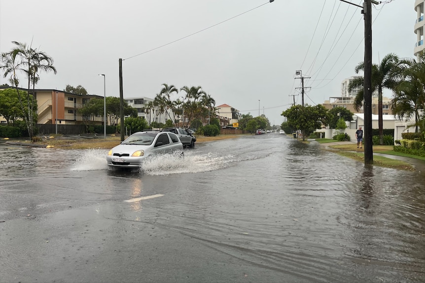 A car drives through a partially flooded street