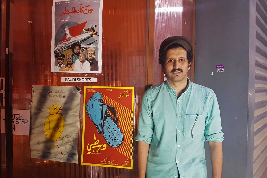 Saudi filmmaker Ali Kalthami stands next to the poster for his film "Wasati" or "Moderate".