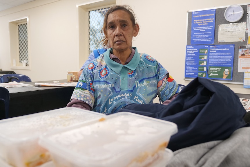 A woman sits with hot meals and clothes