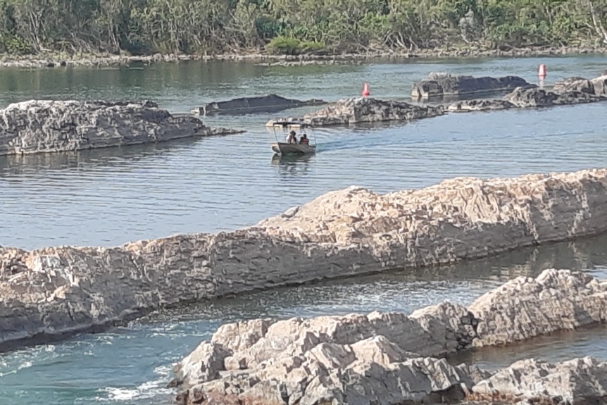 A boat cruises in water between rock bars
