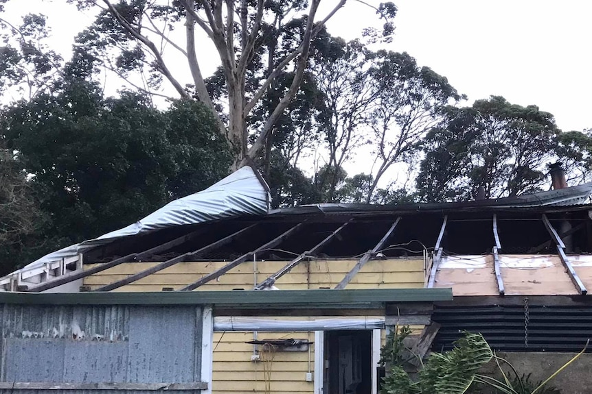 A close-up shot of a house with its tin roof torn off.