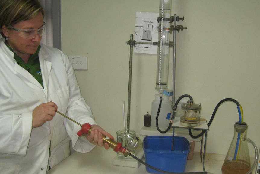 Woman in a white lab coat testing water samples