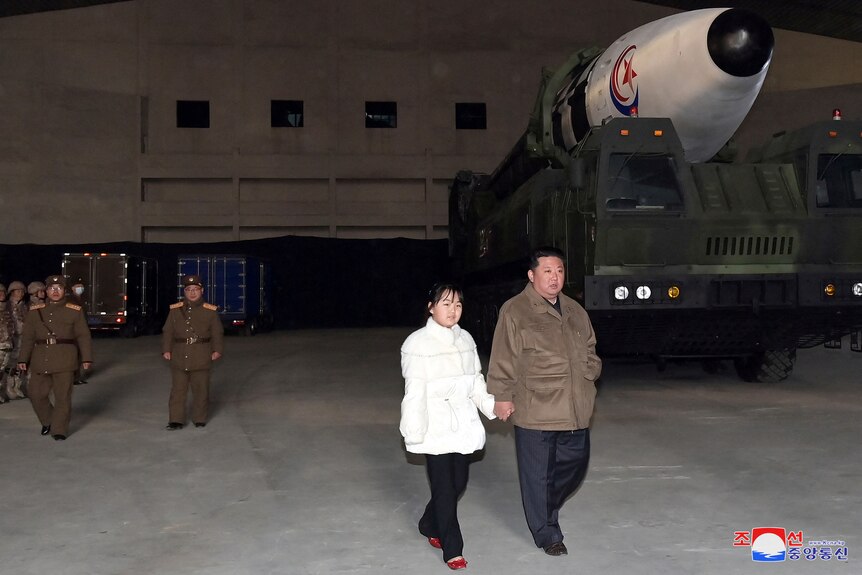 Kim Jong Un and his daughter walk away from a truck carrying a missile. 