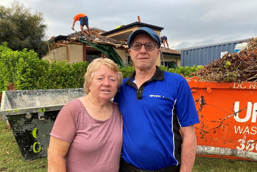 Couple stand in front of their damaged home at Springfield Lakes.