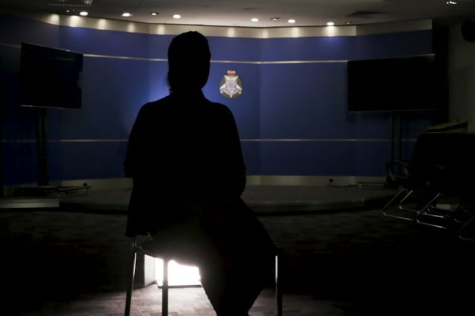 A woman in silhouette in a Victoria Police media room.