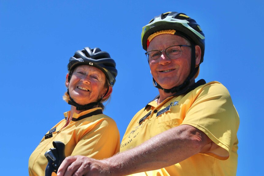 Two cyclists in yellow shirts smiling at the camera