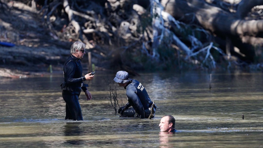 Emergency services workers in wet suits in the river.