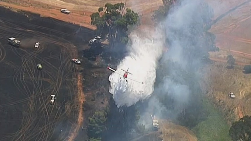 A water bombing aircraft dumps water on a grassfire.