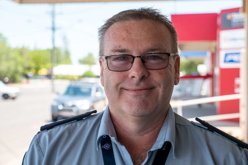 A middle-aged man with glasses in a paramedic's formal uniform smiles at the camera.