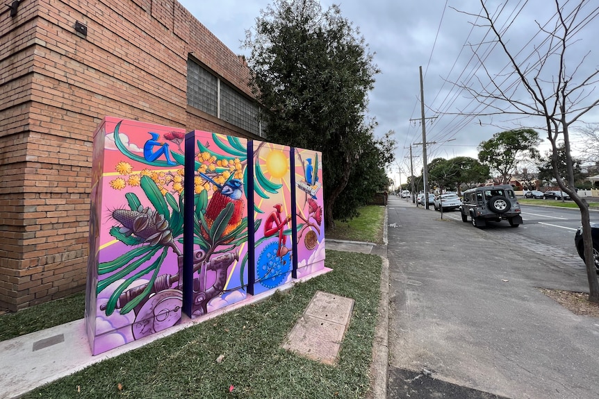 A close-up of mural artwork which has a flower, a bird, and an ethereal figure.