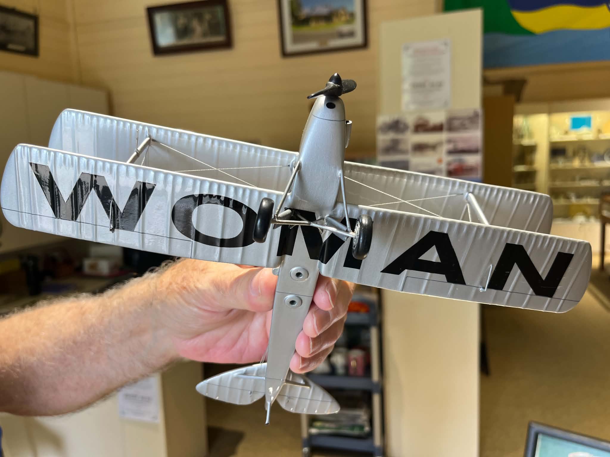 A model plane with WOMAN written in large bold text on the bottom of the wings.