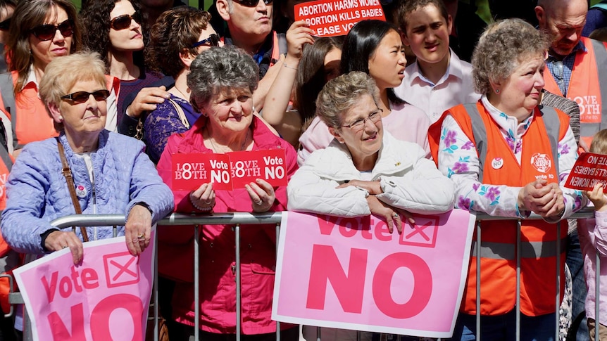 Women hold Vote No signs.