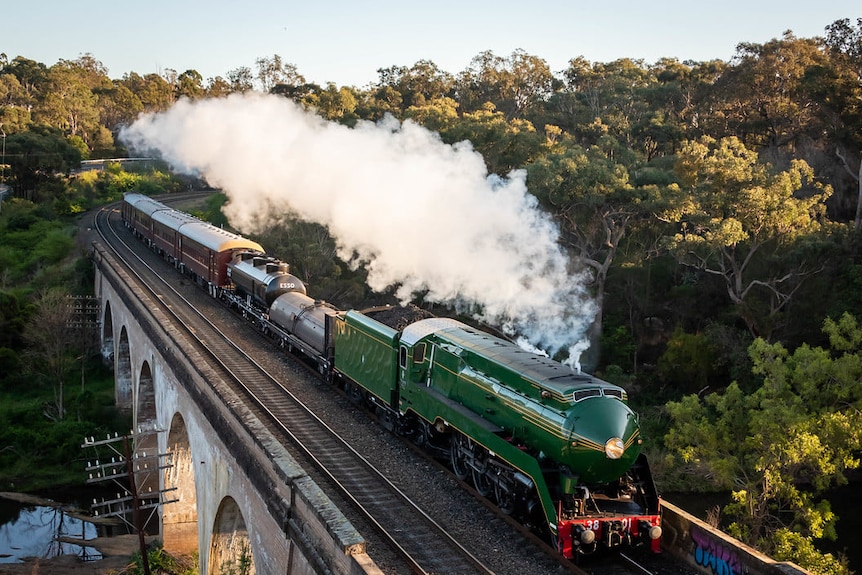 Steam comes off train while it crosses bridge