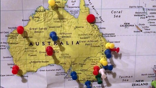 A map of Australia with many thumb tacks placed in it.