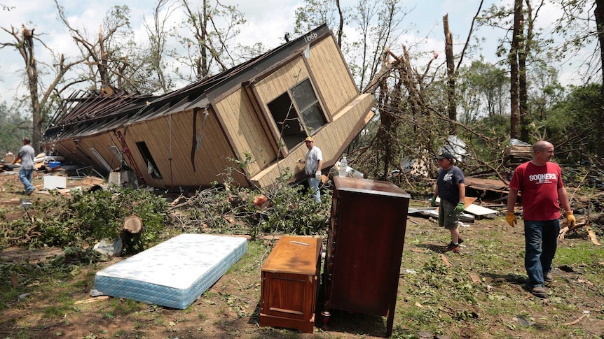 Volunteers help clean out Jean McAdams' mobile home after it was overturned by a tornado.