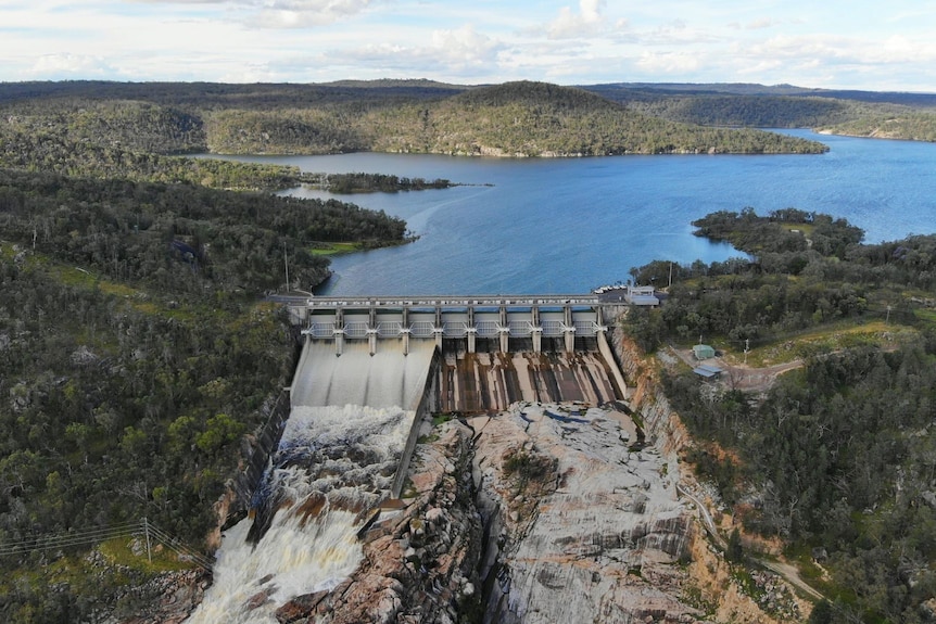 Full dam with water spilling over the wall.