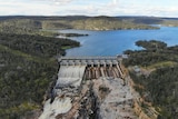 Full dam with water spilling over the wall.