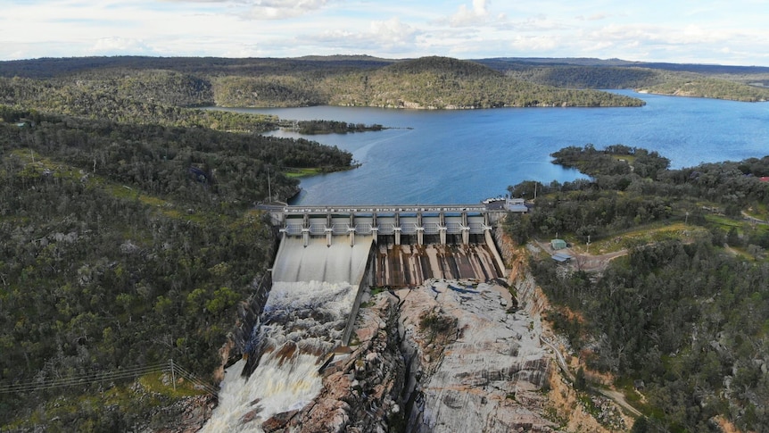 Full dam with water spilling over the wall.