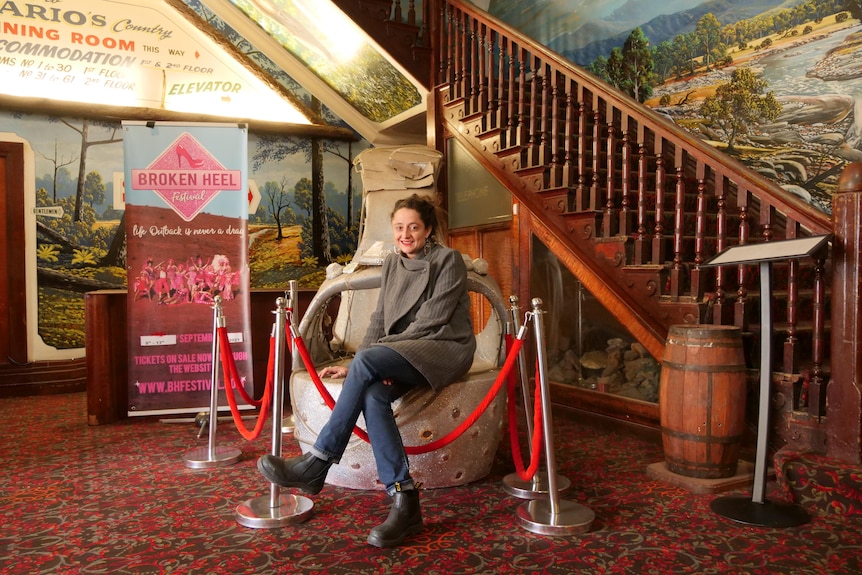 A woman sits in a hotel lobby surrounded by posters