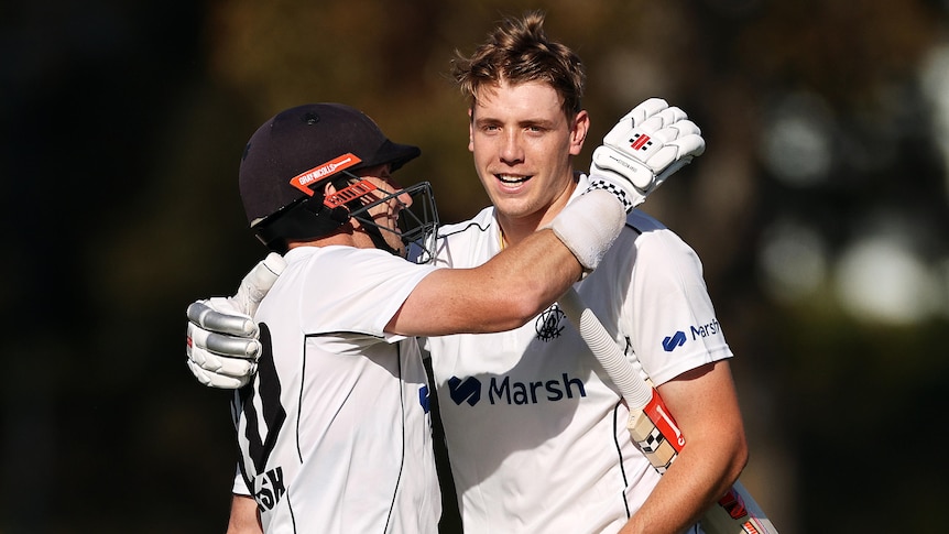 Two male cricketers embrace as they celebrate a Sheffield Shield century.