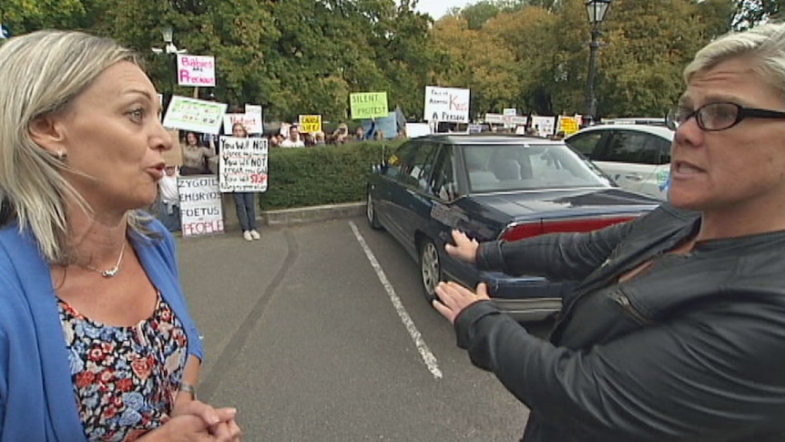 A Tasmanian school teacher clashes with a member of the public as school children protest against abortion.