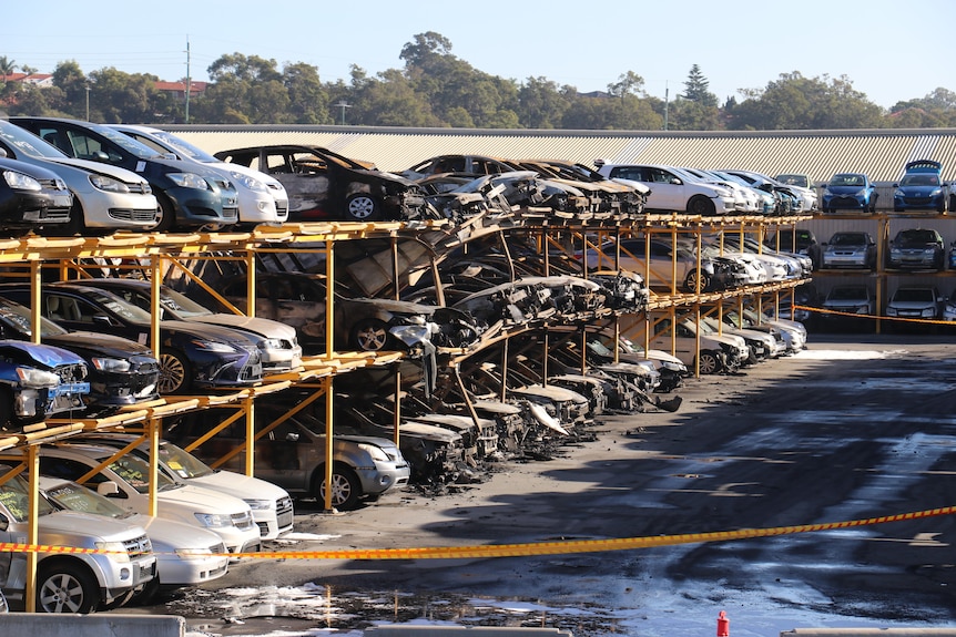 A row of cars stacked three high that have been burned and destroyed. 