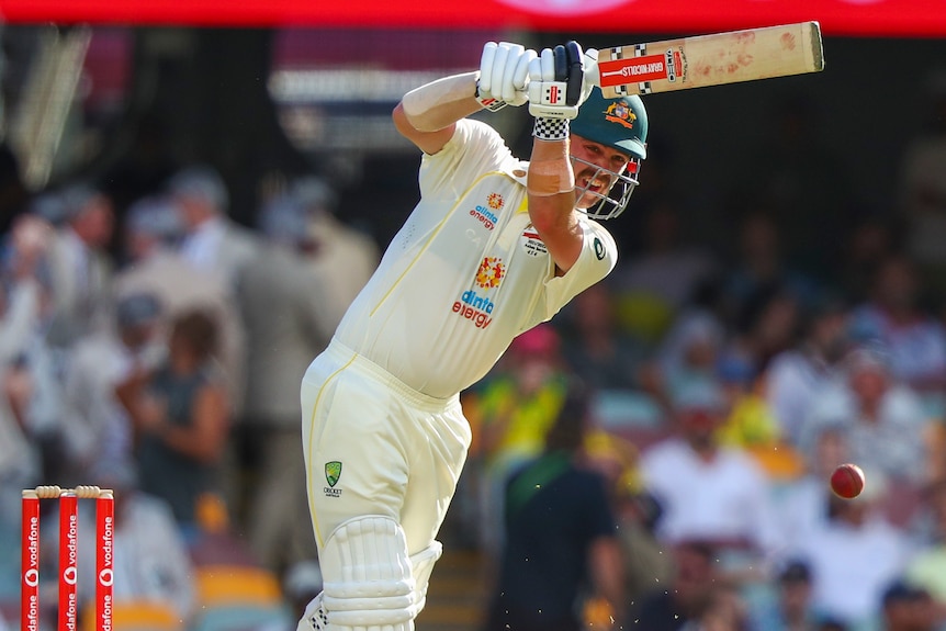 Australian cricket player Travis Head raises his bat for an oncoming ball.