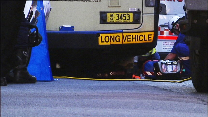 Ambulance officers work to free a woman trapped under a bus in Sydney's CBD