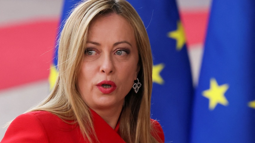 a closeup of Meloni's face as she stands in front of EU flags