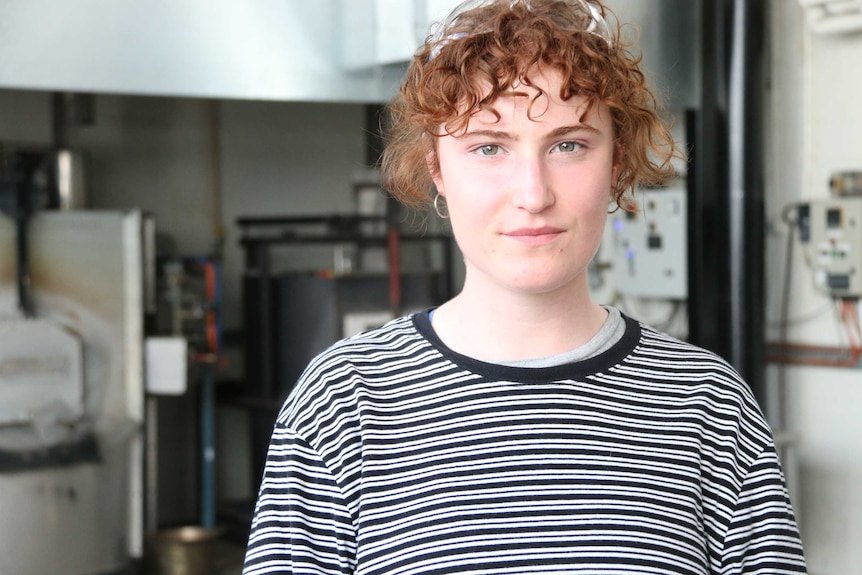 Broni stands in her workshop and looks into the camera.