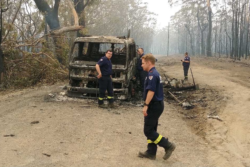 Fire fighters inspect the charred shell of a burnt out fire truck.