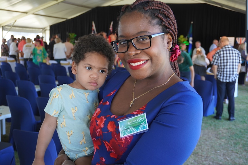 a smiling woman holds a toddler on her hip