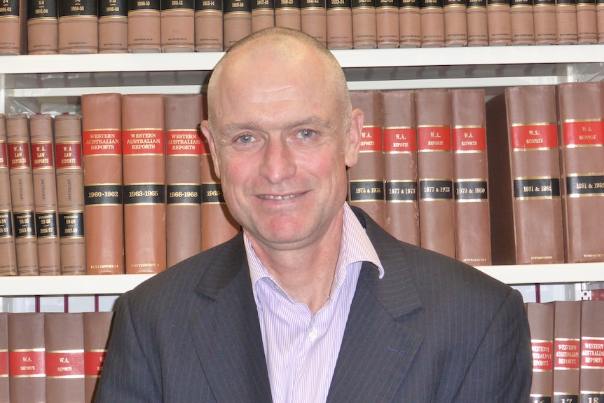 A man posing in front of legal books.