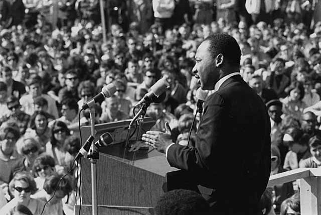 Martin luther king jnr addresses a large crowd from a podium