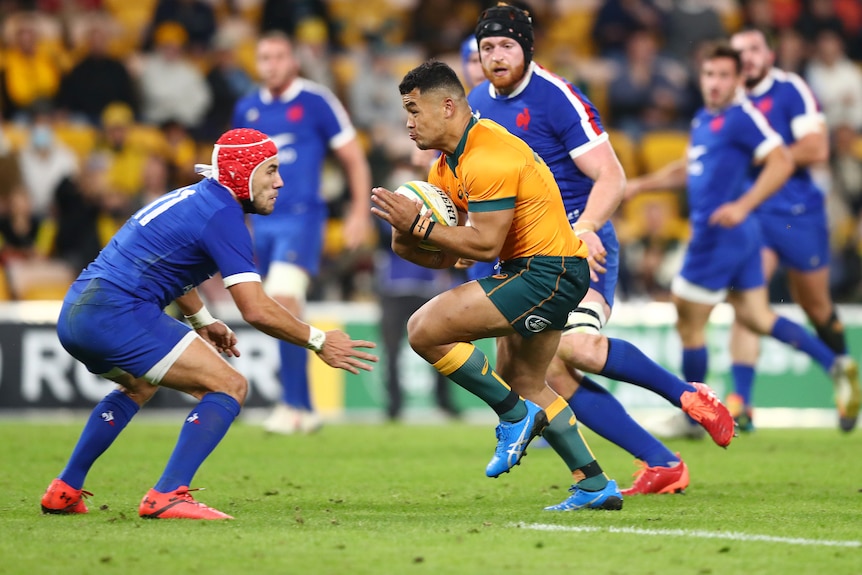 A French player in headgear prepares to tackle a Wallabies player.