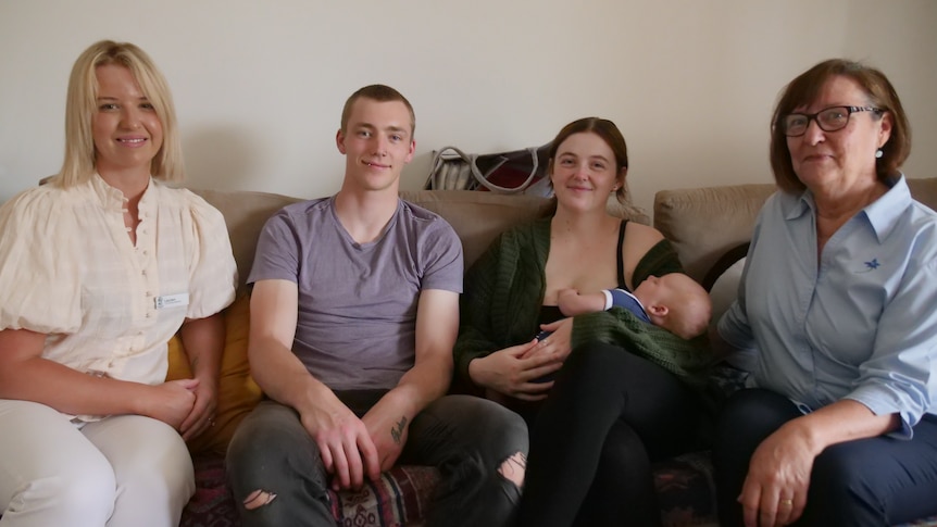 Four adults and a baby smile for the camera on a couch