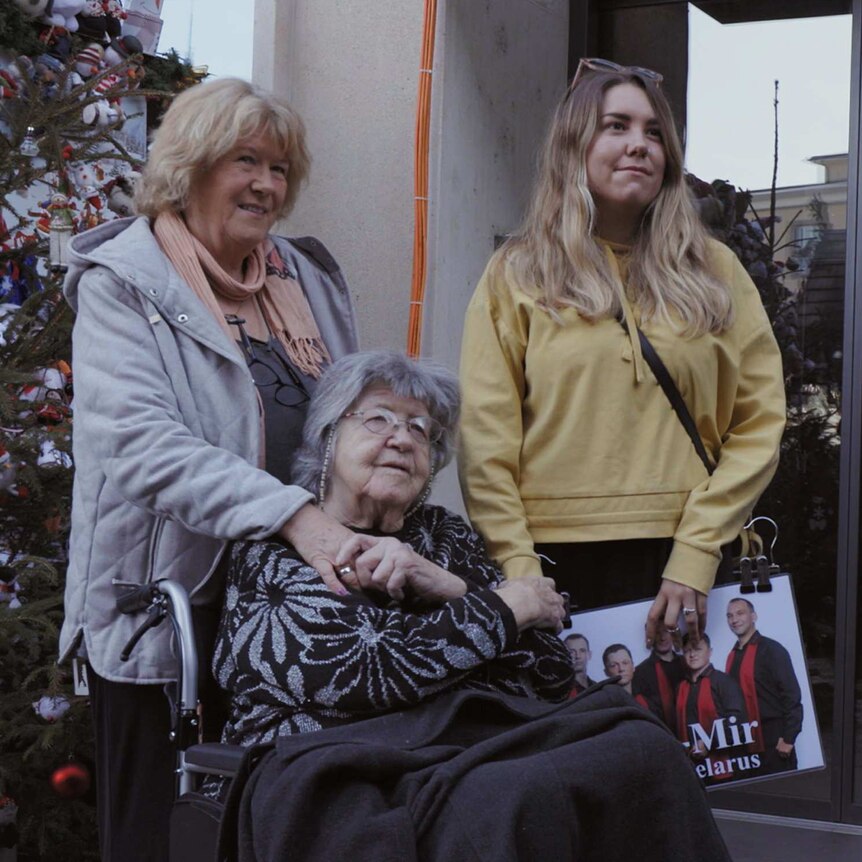 Filmmakers Cathy Henkel and Sam Lara stand by their grandmother Laura Henkel as she sits in her wheelchair