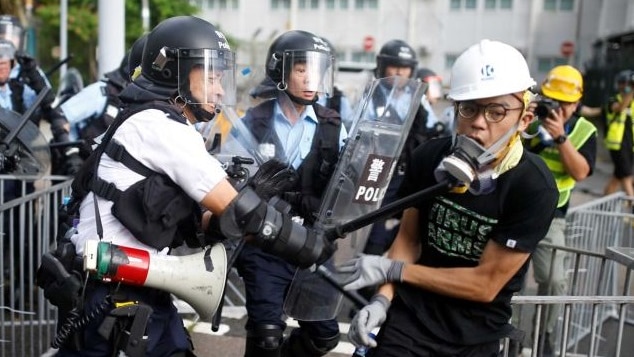 A police officer strikes a protester with a baton on the anniversary of Hong Kong handover to China.