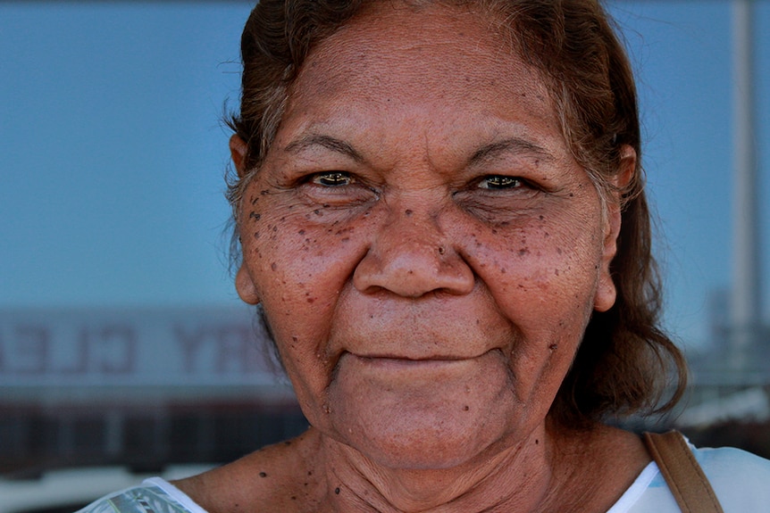 An Aboriginal woman looks straight at the camera, head and shoulders portrait.