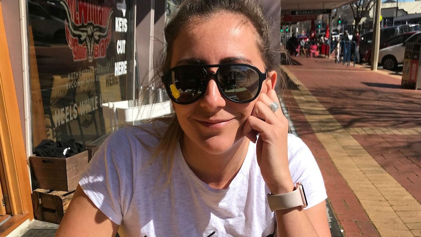 Tara Leach wearing sunnies as she smiles at a cafe.