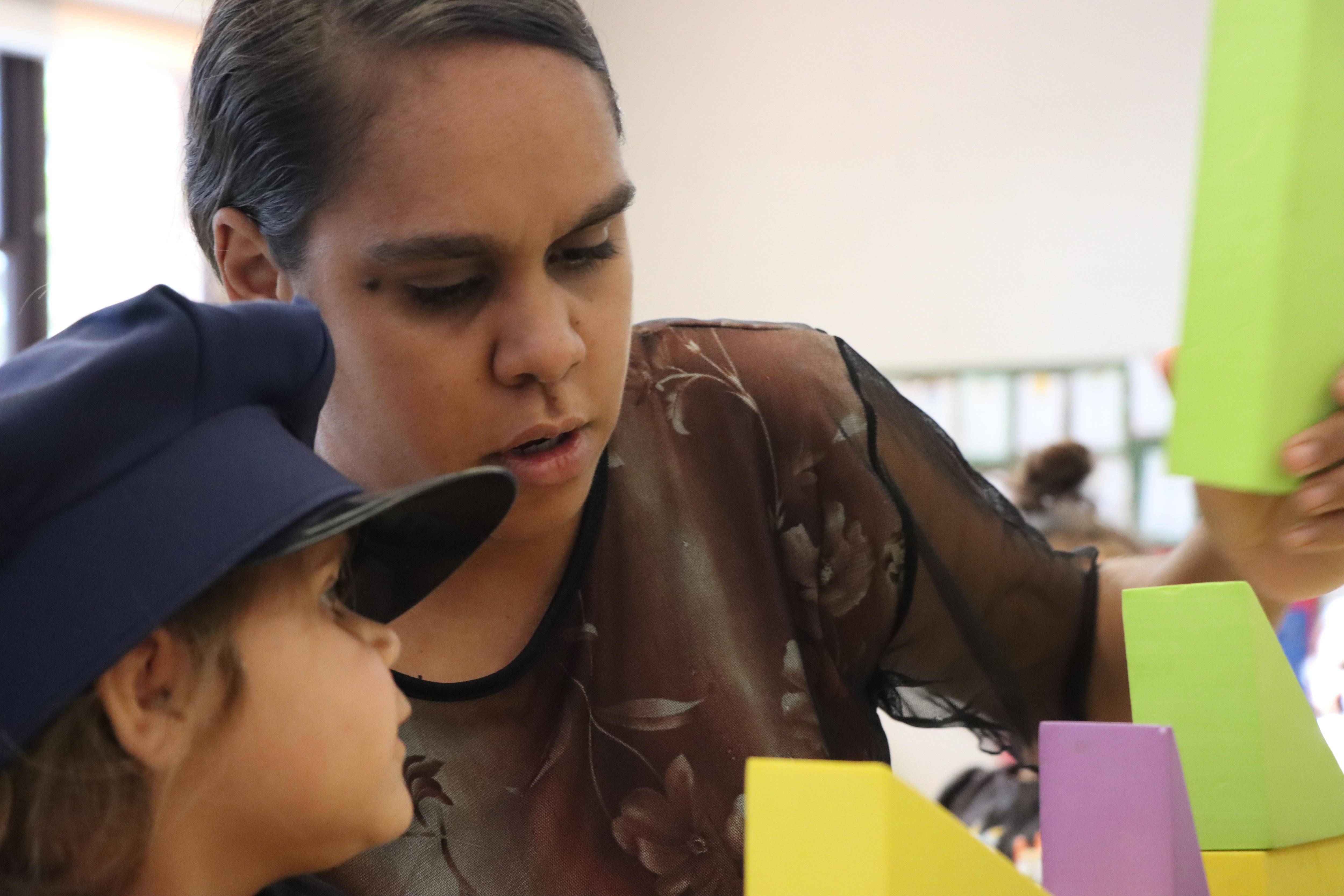 A woman plays blocks with a child.