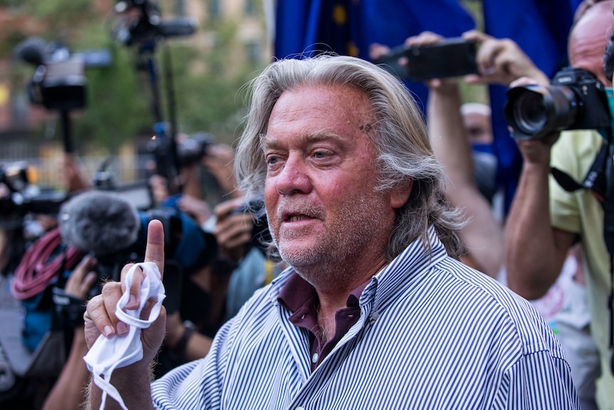 Steve Bannon gestures while speaking in front of reporters