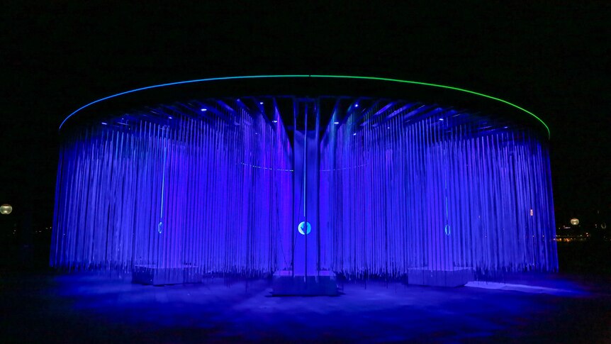 A curtain of blue lights hang in a circle creating a curtain of colour in a sydney park at night.