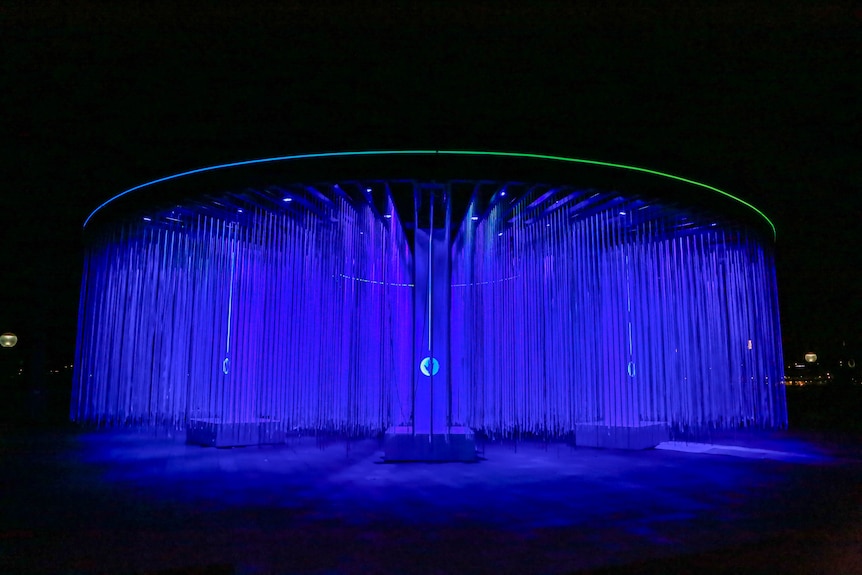 A curtain of blue lights hang in a circle creating a curtain of colour in a sydney park at night.